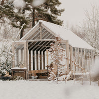 Wooden shed covered in snow with trees in the background