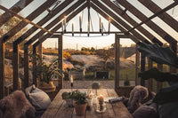 Cozy indoor setting with wooden beams, a table with candles and plants, and a scenic outdoor view.