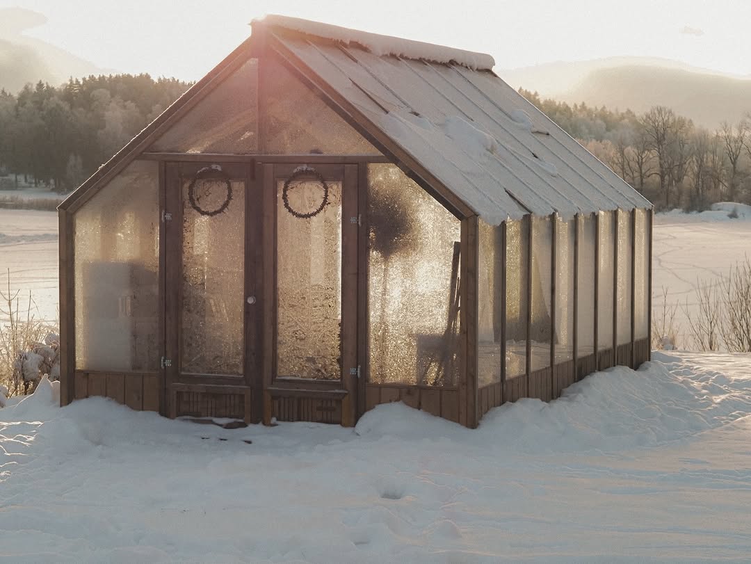 Greenhouse in a snowy landscape with mountains in the background