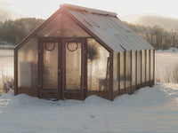 Greenhouse in a snowy landscape with mountains in the background