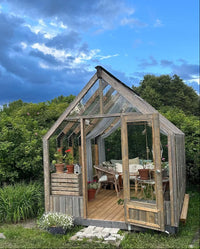 Wooden greenhouse in a garden with a clear blue sky