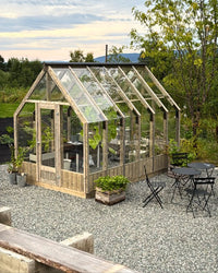 Greenhouse with outdoor seating area in a garden setting