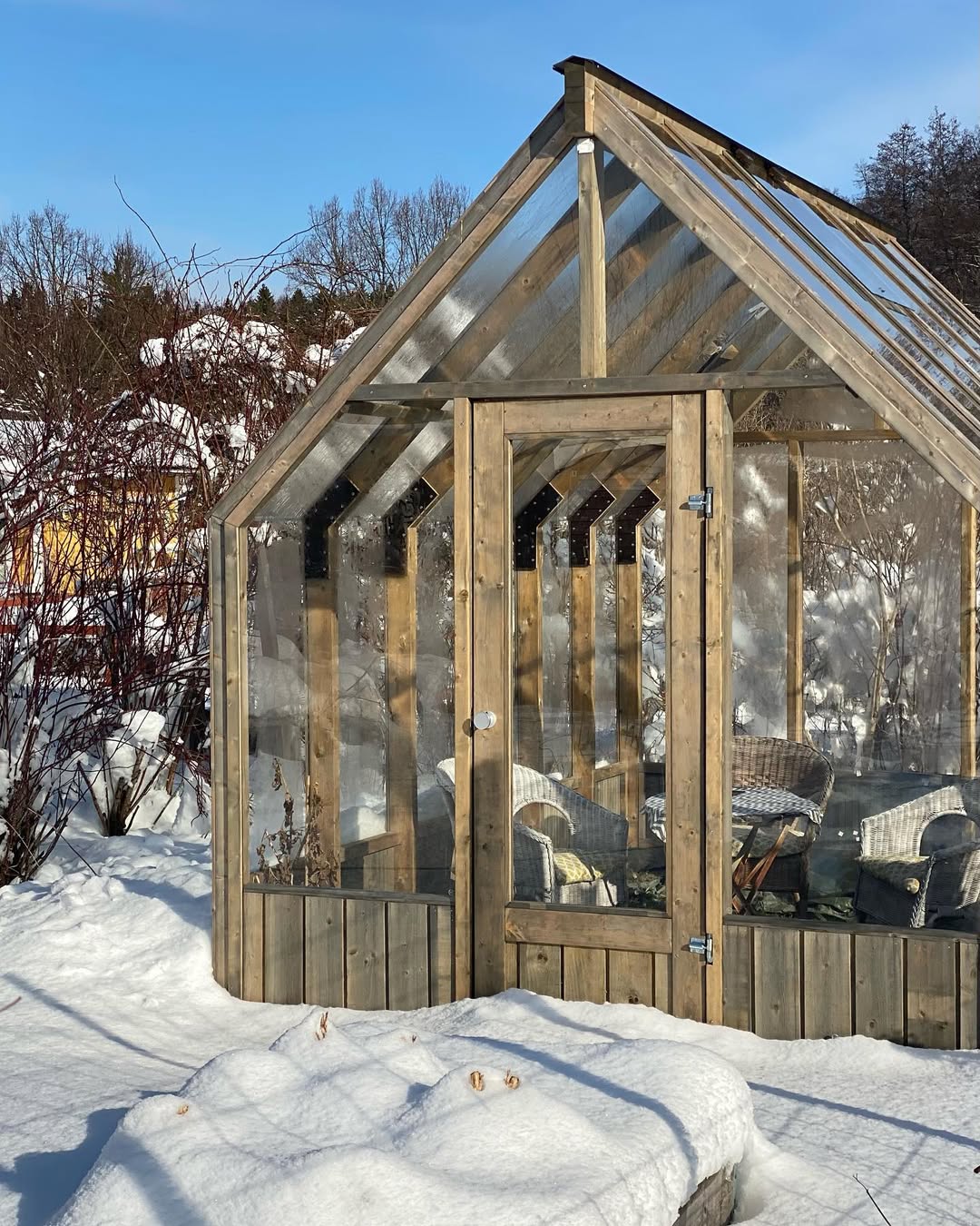 Wooden greenhouse with transparent roof in a snowy outdoor setting