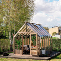 Wooden greenhouse with interior furniture in a garden setting